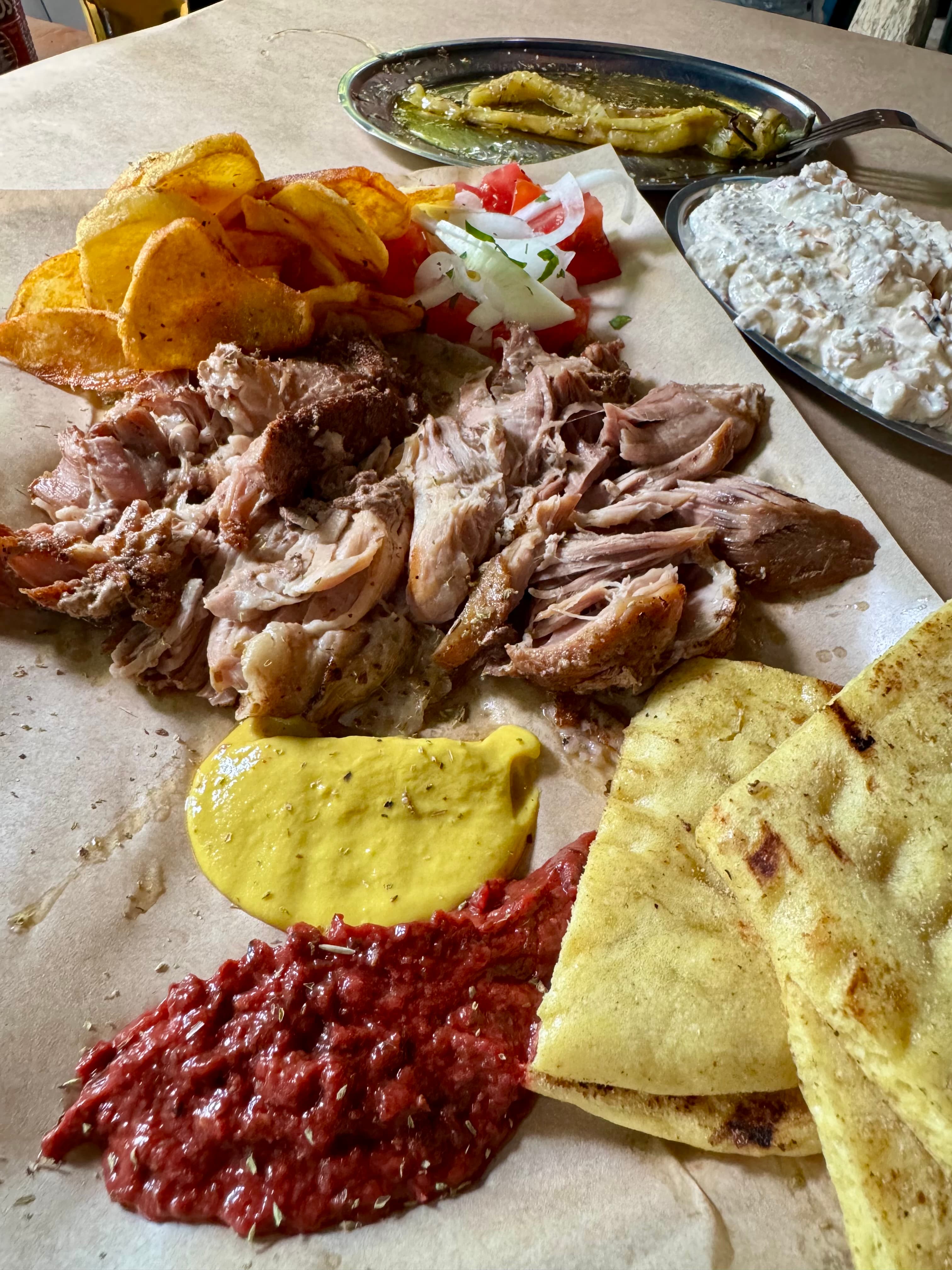 Roast pork in the casserole with fresh fries, mustard, paprika, tomato, onion, and corn pita.