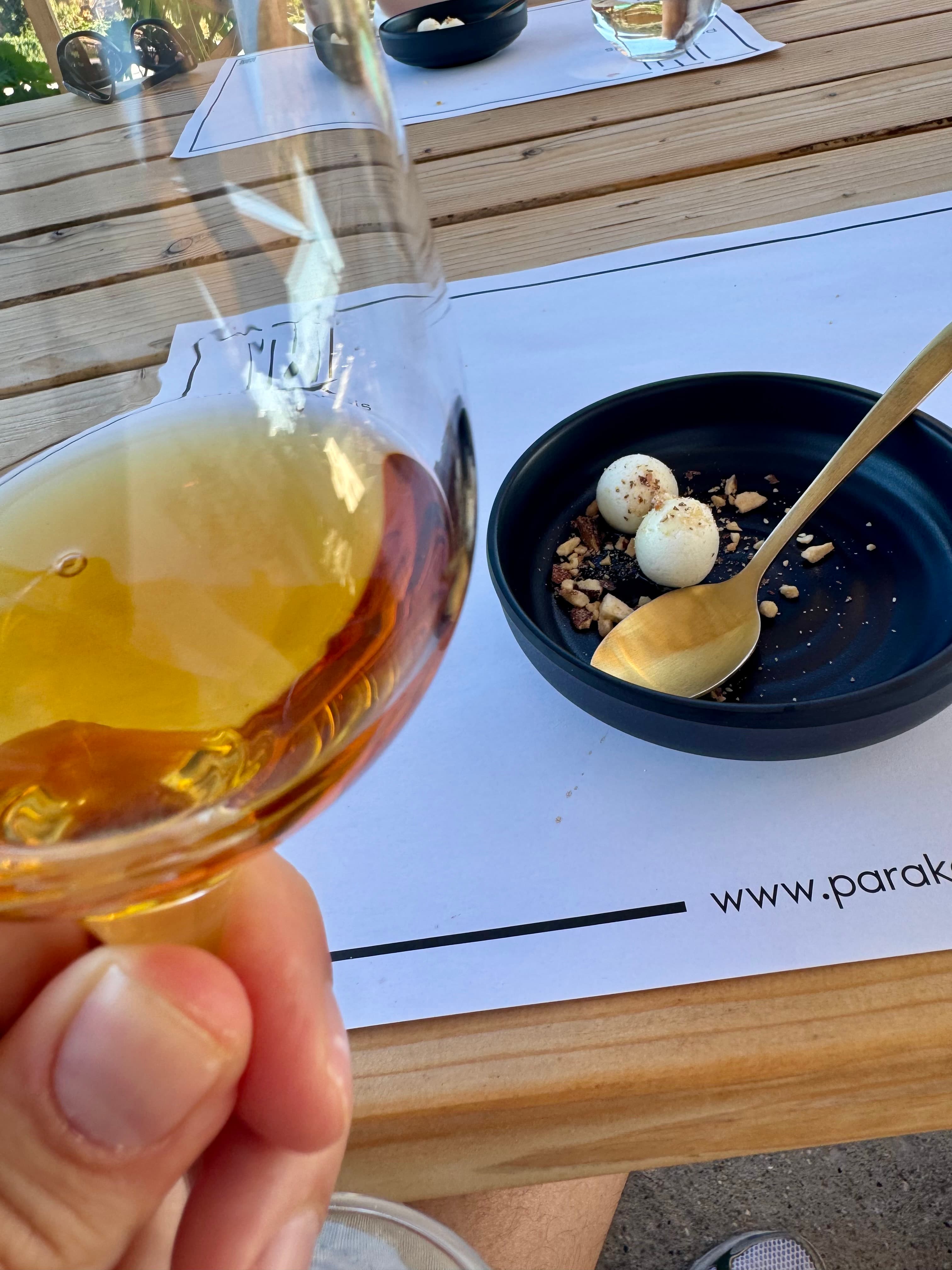 A glass of **Ambito** served with goat cheese, toasted almonds, and honey.