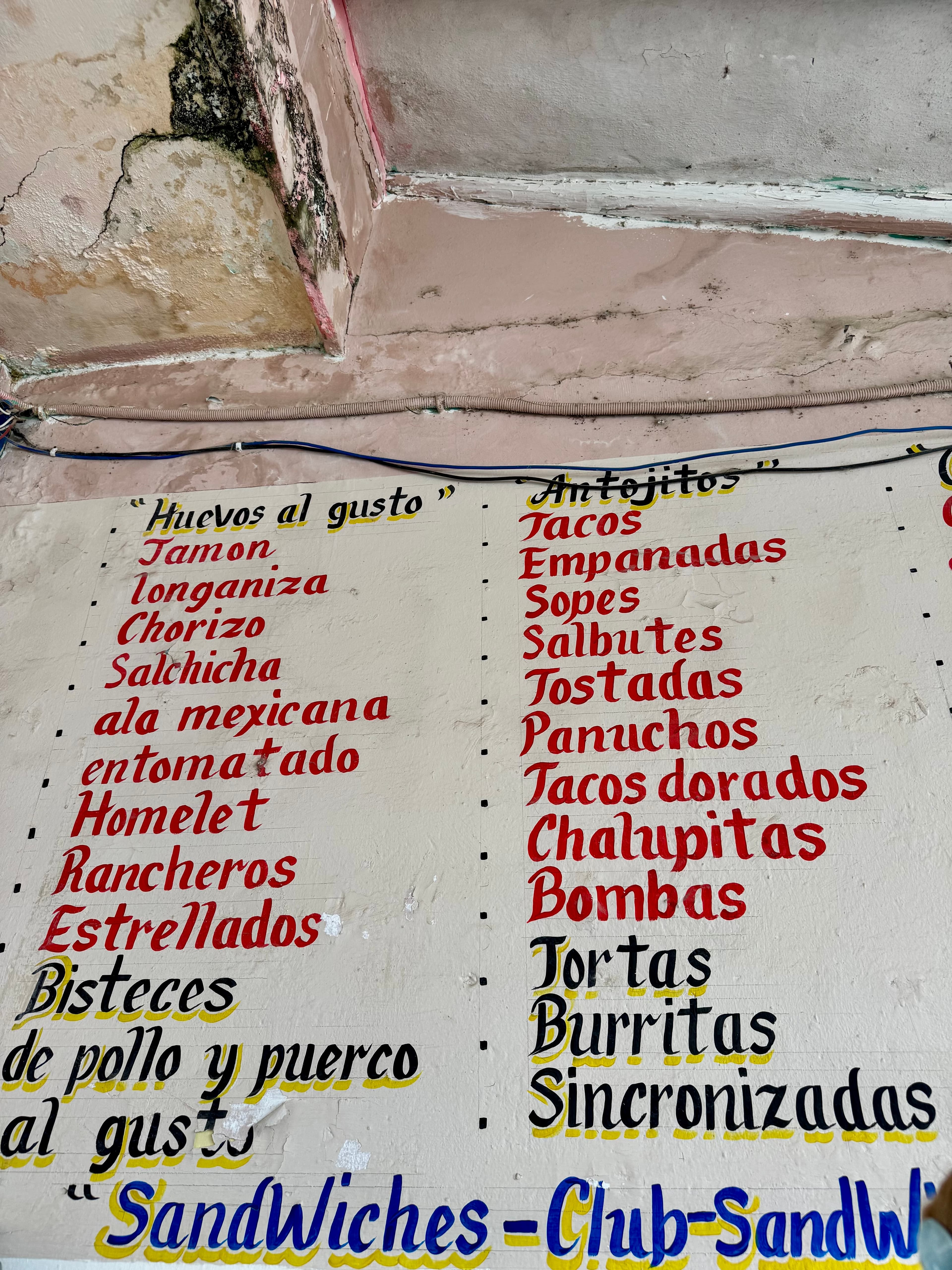 The menu painted on the wall of the small shop that offers food at low prices.